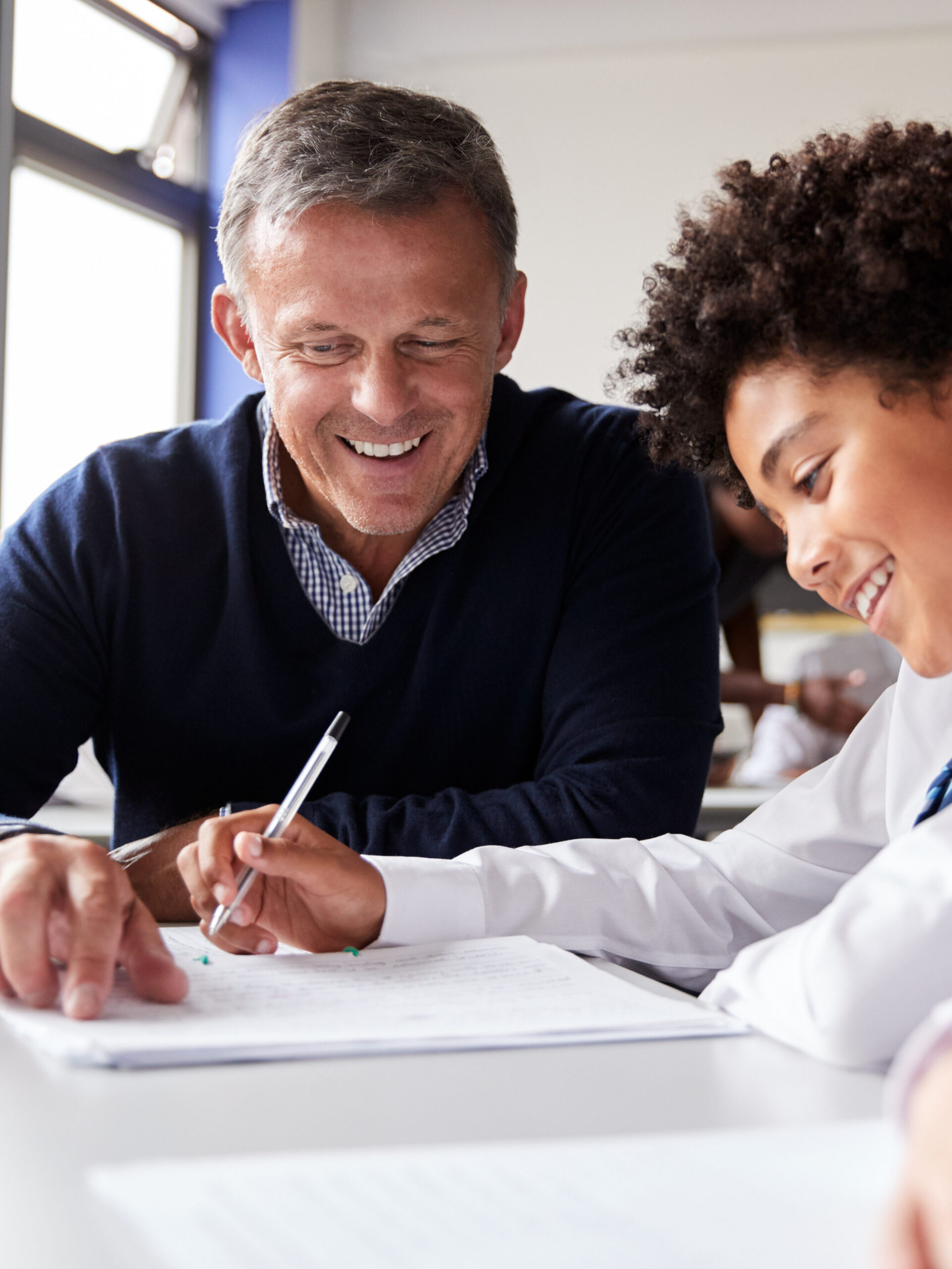 A teacher helping a student at a desk