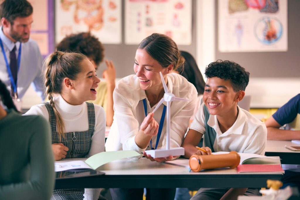 A teacher laughing with her students during a classroom activity
